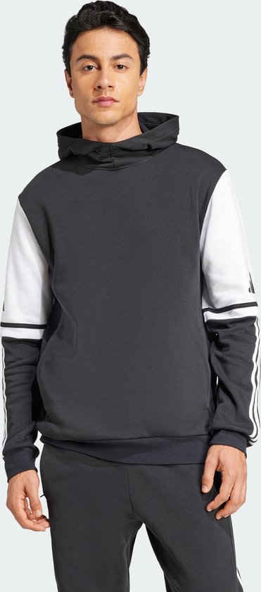 Man met een donkergrijs sweatshirt met witte mouwen en Adidas-strepen op de mouwen.