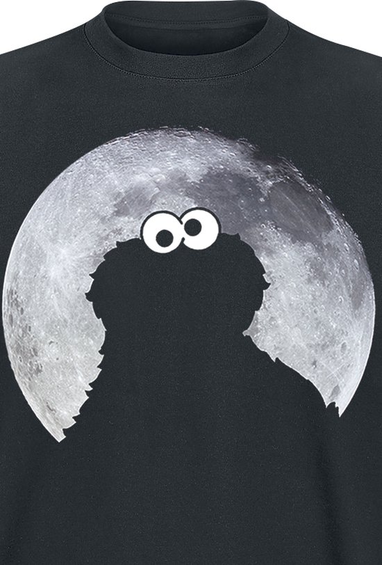 Detail van een zwart t-shirt met op de voorkant een silhouet van Cookie Monster met grote ogen tegen een volle maan.