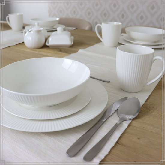 Witte OTIX servies op een houten tafel met placemats, bestaande uit kommen, borden en mokken.