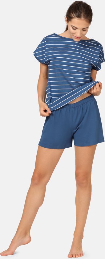 Vrouw toont een blauwe pyjamaset met strepen op het shirt en een effen blauwe korte broek.