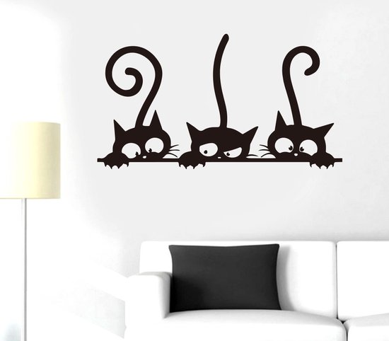 Zwarte katten sticker op een witte muur boven een witte bank.
