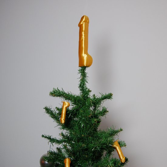 Gouden piemel kerstpiek bovenop een kleine kerstboom, met andere gouden piemels als versiering.