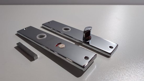Deux plaques de porte argentées avec un indicateur de toilette, à côté d'une petite barre métallique.