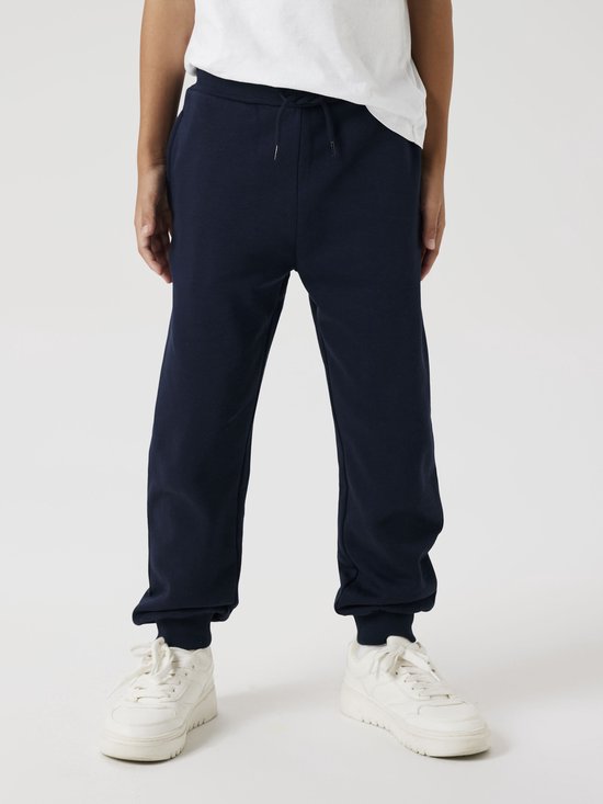 Onderlichaam van een jongen in een donkerblauwe joggingbroek met koord.