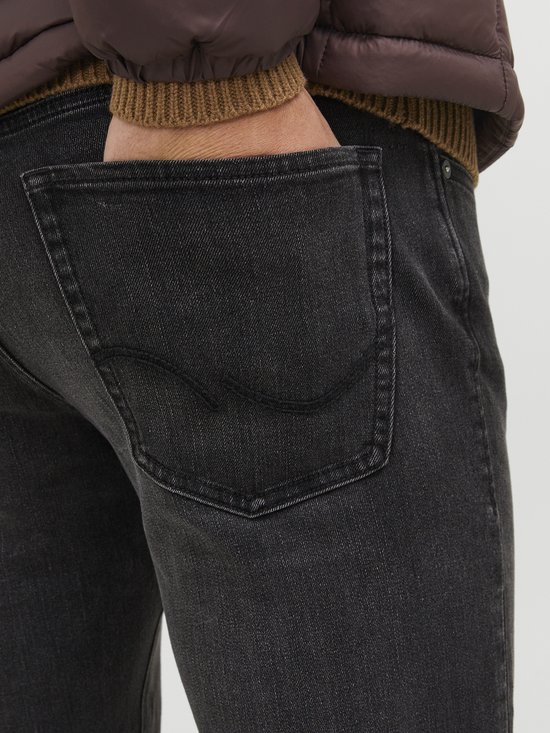 Donkergrijze jeans, detail van de achterzak met zwarte stiksels.