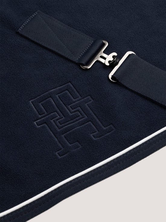 Donkerblauwe deken met TH monogram en gespsluiting.