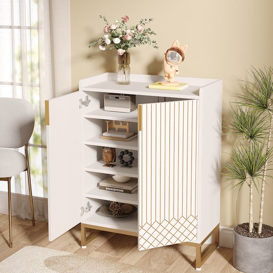 Witte schoenenkast met gouden lijnen, open deuren tonen planken met decoraties. Een plant staat ernaast.