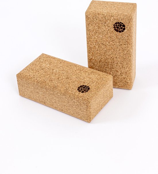 Deux blocs de yoga en liège, l'un posé à plat et l'autre à la verticale, avec des motifs circulaires gravés sur leurs côtés.
