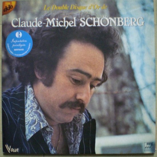 Claude-Michel Schönberg, met snor en krullend haar, draagt een geborduurd jasje. Opdruk Le Double Disque d'Or.