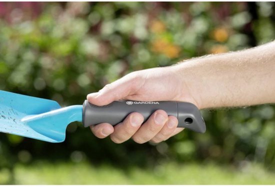 Dichtbij van een hand die een grijs, ergonomisch GARDENA handvat van een tuinschepje vasthoudt.