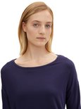Close-up van een donkerblauw T-shirt met lange mouwen en boot hals, gedragen door een blond model.