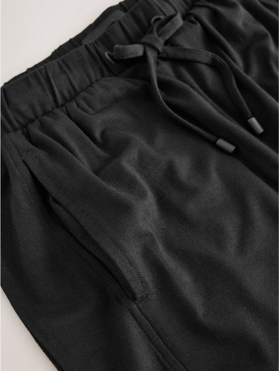 Detail van zwarte joggingbroek met elastische tailleband, trekkoord en zak.