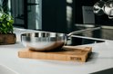 Roestvrijstalen wokpan op een houten snijplank in een keuken.