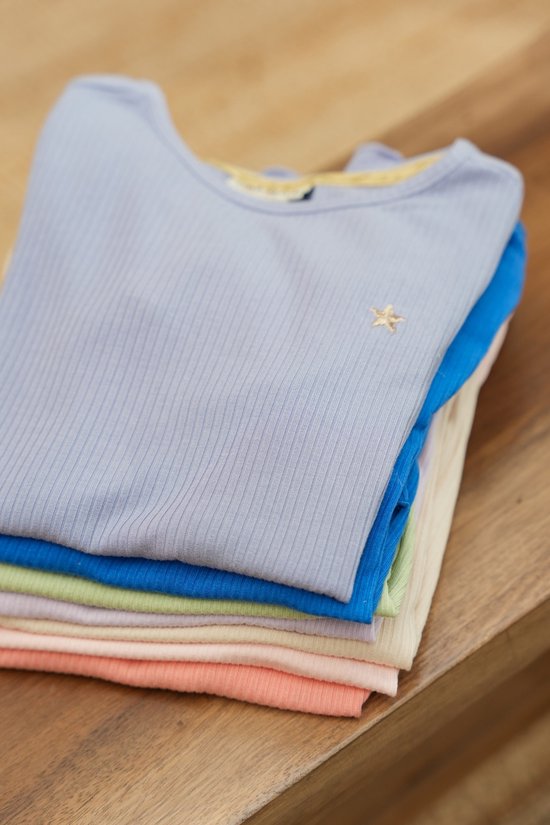 Stapel van effen gekleurde geribbelde T-shirts in pastelkleuren, waaronder lichtblauw, blauw, lichtgroen, perzik en crème. Eén T-shirt met ster applicatie zichtbaar.