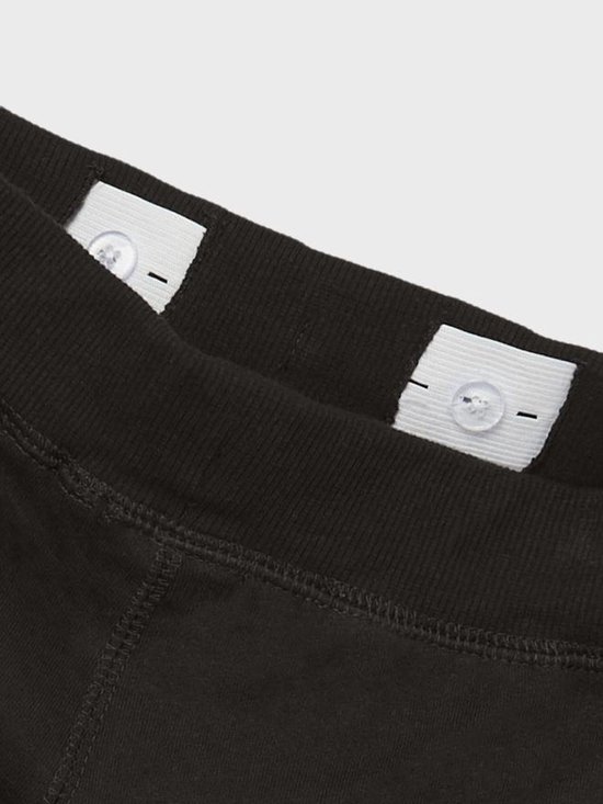Detail van de binnenkant van de tailleband van een zwarte joggingbroek met knopen voor verstelling.
