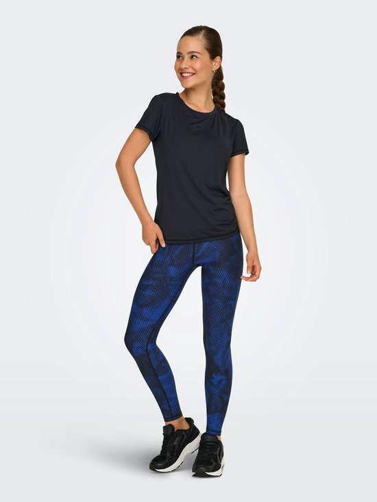 Model draagt zwart t-shirt met korte mouwen en ronde hals, gecombineerd met een blauw-zwarte legging.