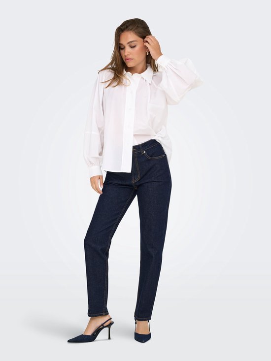 Model in een rechtvallende donkerblauwe jeans met een hoge taille en een witte blouse.