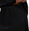 Femme portant une jupe en satin noir, gros plan de la taille.