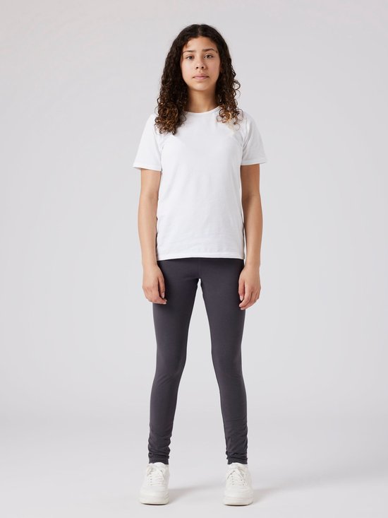 Een meisje met krullend haar in een witte t-shirt en antrgrijze legging.