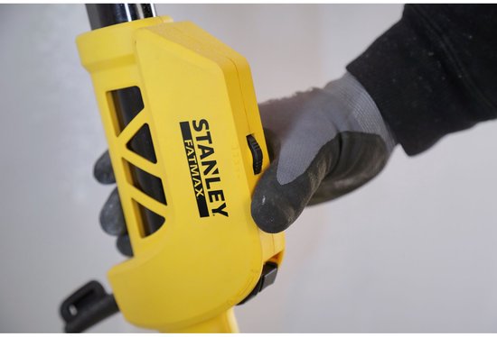 Hand met grijze handschoen bedient een schuifknop op de gele Stanley Fatmax schuurmachine.