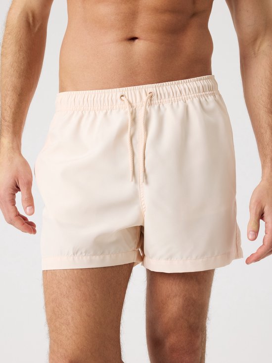 Lichtroze zwembroek met trekkoord en elastische tailleband, getoond op een man.