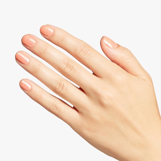 Close-up van een vrouwelijke hand met glinsterende perzikkleurige nagellak.