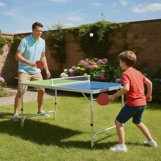 Man en jongen spelen tafeltennis in de tuin op een blauwgroene tafel. Rode en zwarte batjes.