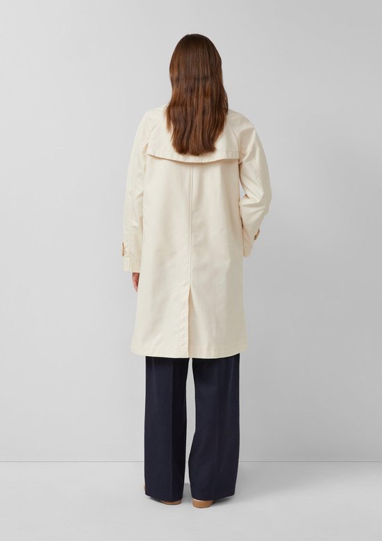 Vrouw met de rug naar de camera, in een crèmekleurige s.Oliver trenchcoat.
