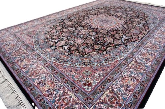 Gedetailleerd perzisch vloerkleed in zwart met bloemenpatronen in roze, blauw en crèmekleur. Hoek weergave met franje.