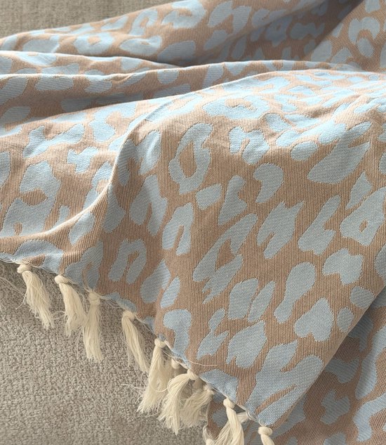 Detail van een lichtblauwe panterprint op bruine plaid met witte franjes.