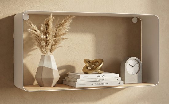 Wit wandrek met een vaas met pampasgras, boeken en een gouden decoratieobject.