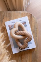 Twee in elkaar gedraaide, houten harten op een tijdschrift op een houten tafel.