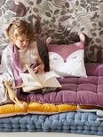 Meisje leest op een paarse matras met een kussen in de vorm van een vos.