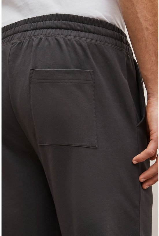 Close-up van de achterkant van een donkergrijze joggingbroek met een opgestikte zak.