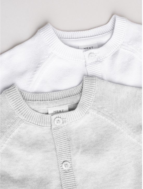 Detail van de ronde hals en knopen van een wit en een lichtgrijs babyvestje.