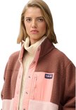 Model draagt bruine, roze en lichtroze fleece jas met hoge kraag.