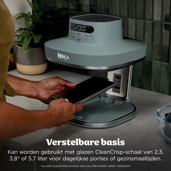 Vrouw plaatst een platte zwarte plaat in een grijze Ninja airfryer. Tekst: Verstelbare basis.