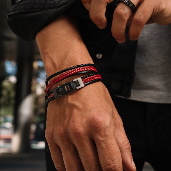 Man die een leren armband met zwart en rood vlechtwerk en een zwarte gesp met leeuwenlogo draagt.