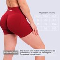 Close-up van de achterkant van een vrouw in een rode sportshort, met een maattabel voor de taille en heup.