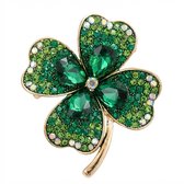 Gouden klaverbroche bezet met groene en witte strass steentjes.