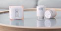 Twee Netatmo slimme thermostaten en een radiatorthermostaat met digitale displays op een glazen tafel.
