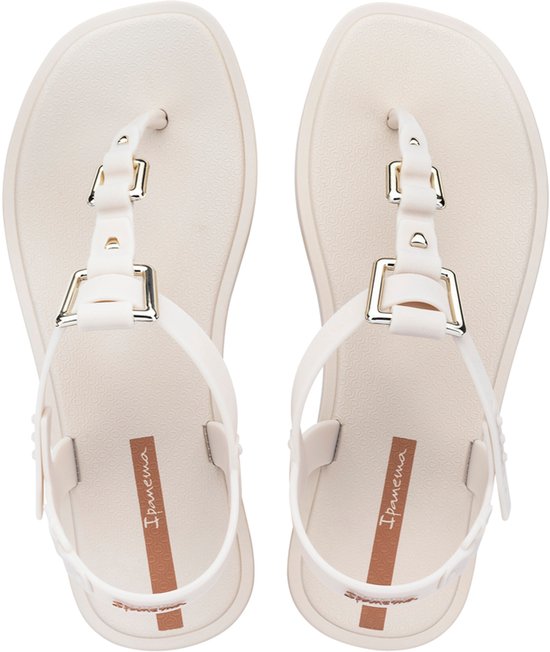 Paar lichtbeige Ipanema slippers, van bovenaf gezien, met enkelbandjes en banden over de wreef met gouden gespen.