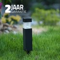 Zwarte vierkante tuinlamp met geribd glazen kap, staand in gras, met '2 jaar garantie' logo.