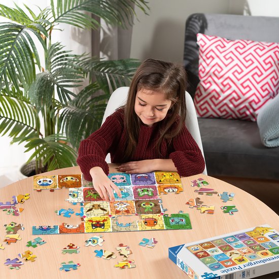Een jong meisje met een bordeauxrode trui puzzelt aan de tafel met het Pokémon Gezichten 100 XXL stukjes Ravensburger puzzel.