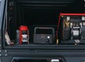 Donkergrijs Jackery Explorer 500 powerstation met oranje accenten, naast een koffiezetapparaat en koelkast in een voertuig.