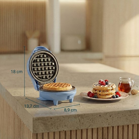 Blauw wafelijzer met afmetingen, ernaast een stapel wafels met bessen en een schaaltje honing.