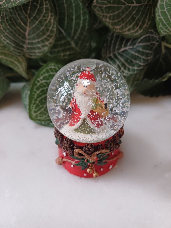 Boule à neige Père Noël sur socle rouge décorée d'un nœud et de pommes de pin 4,5x4,5x6,5cm