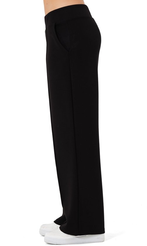 Zijzicht van zwarte wijde broek met rechte pijpen, zakken en witte sneakers.