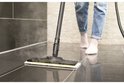 Gros plan du nettoyeur vapeur nettoyant un sol carrelé gris foncé.