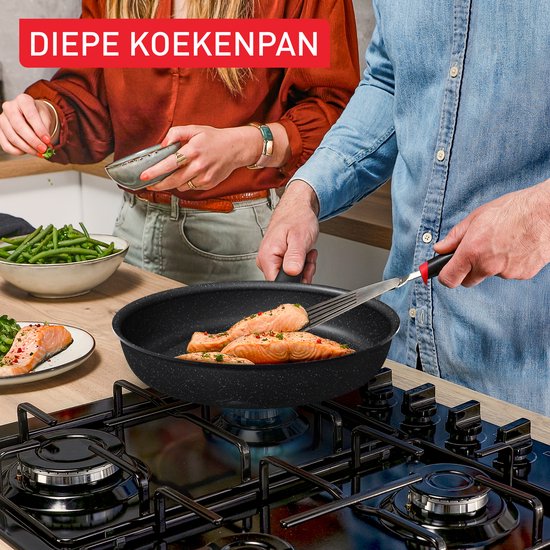 Diepe koekenpan met twee zalmfilets die worden omgedraaid met een spatel.